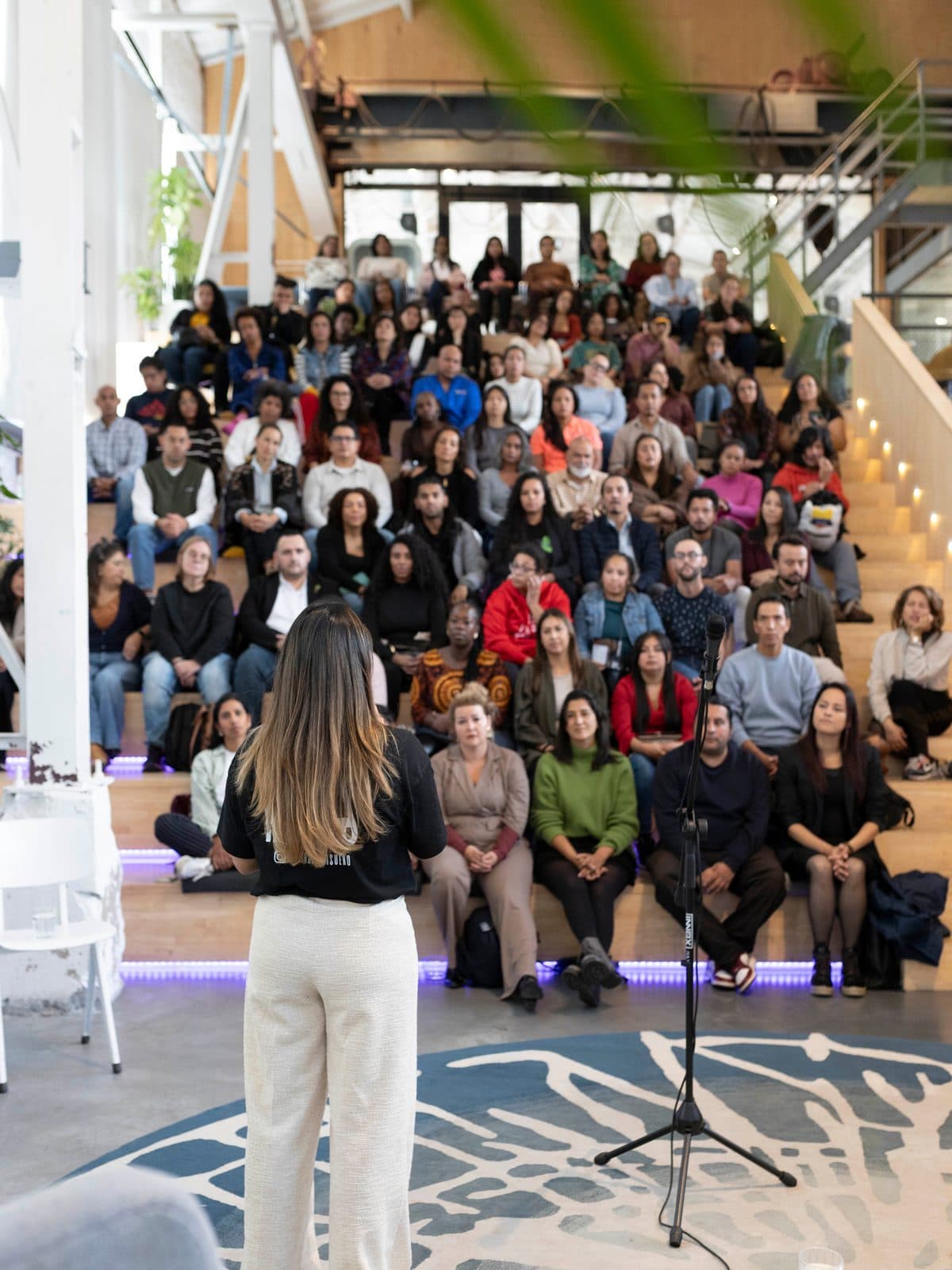 Andrea González Duarte, van achteren gezien, voor een volle zaal publiek